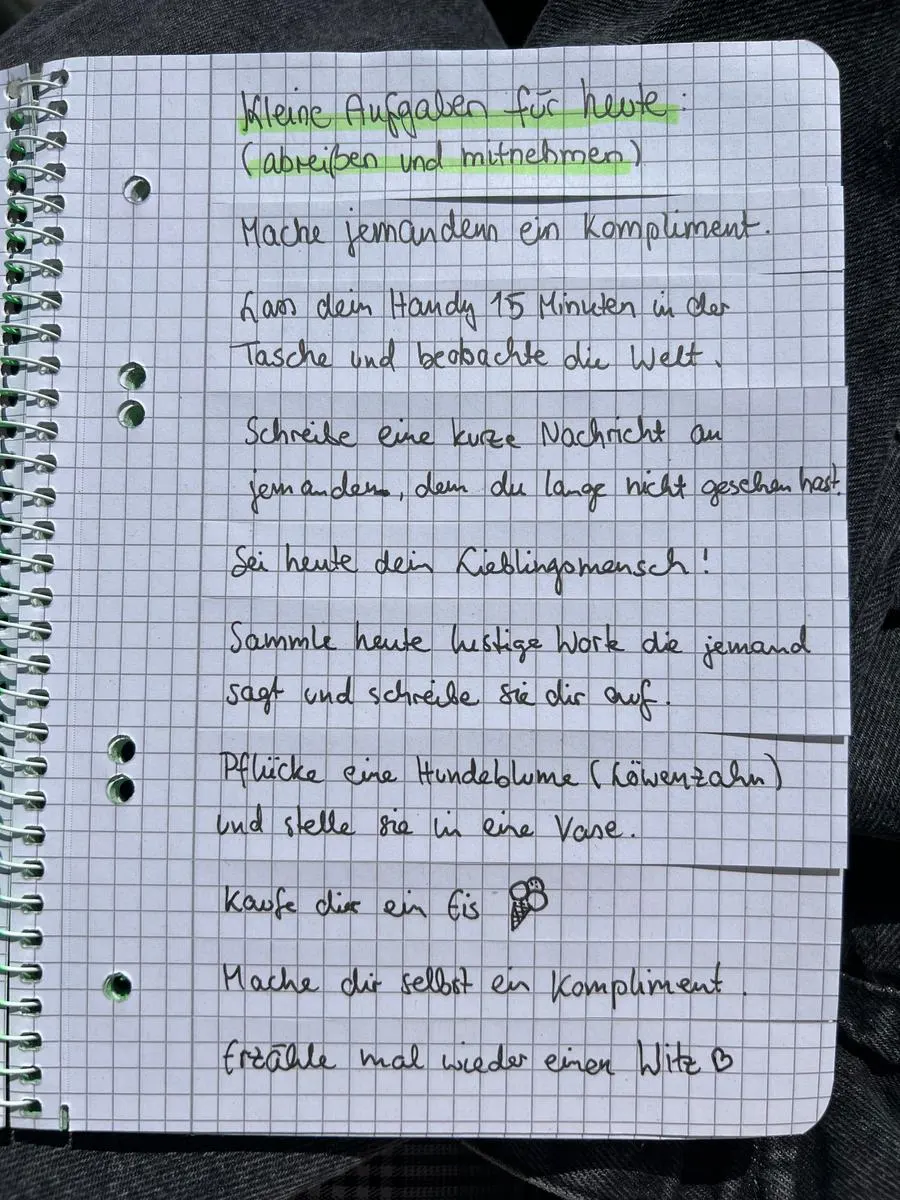 Gästebuchseite „Kleine Aufgaben für heute (abreißen und mitnehmen)“ mit Streifen wie „Mache jemandem ein Kompliment“ und „Pflücke eine Hundeblume und stelle sie in eine Vase“.