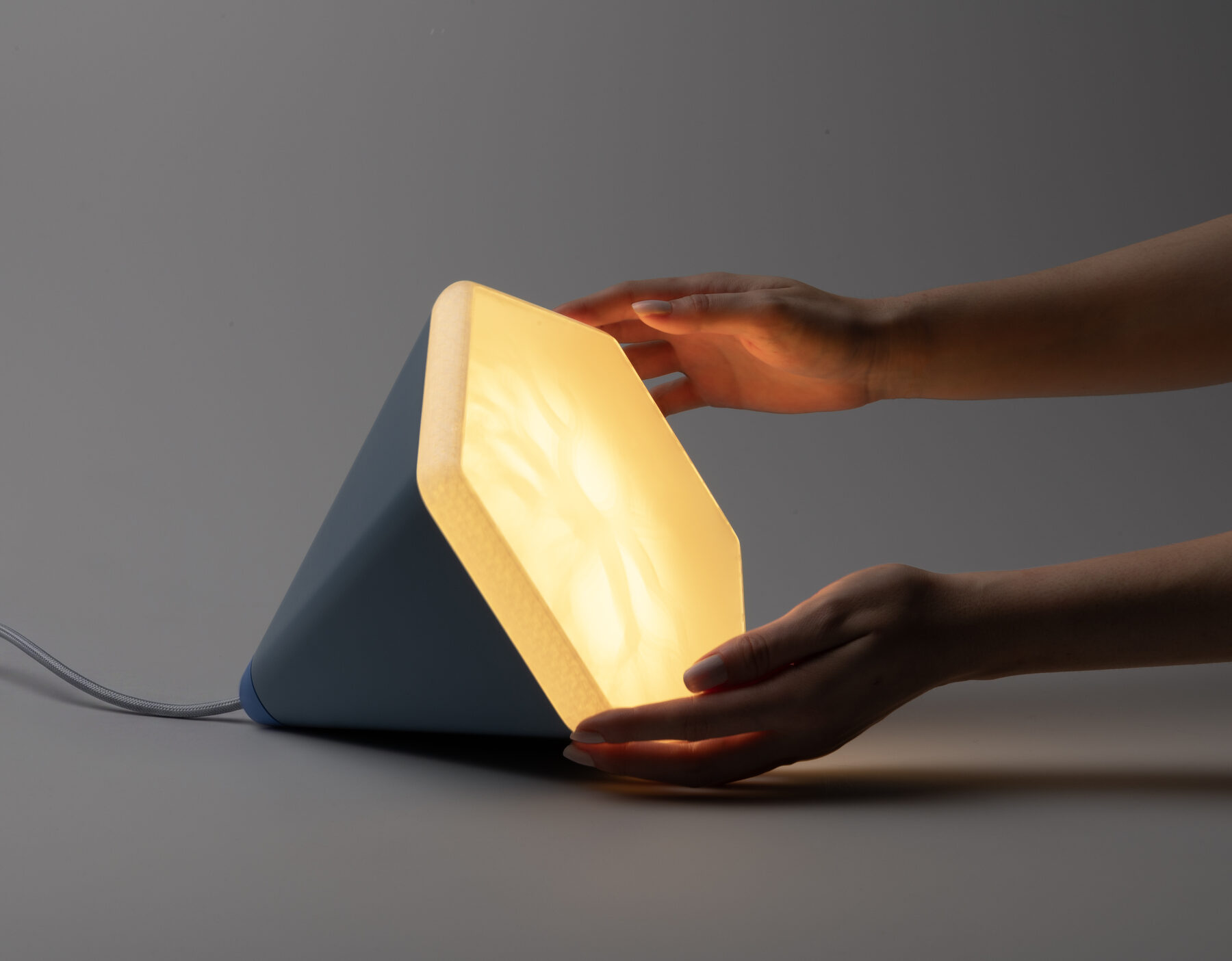 Zwei Hände drehen die Leuchte in eine andere Lage, um per Gyroskop-Sensor das Lichtprogramm zu wechseln.